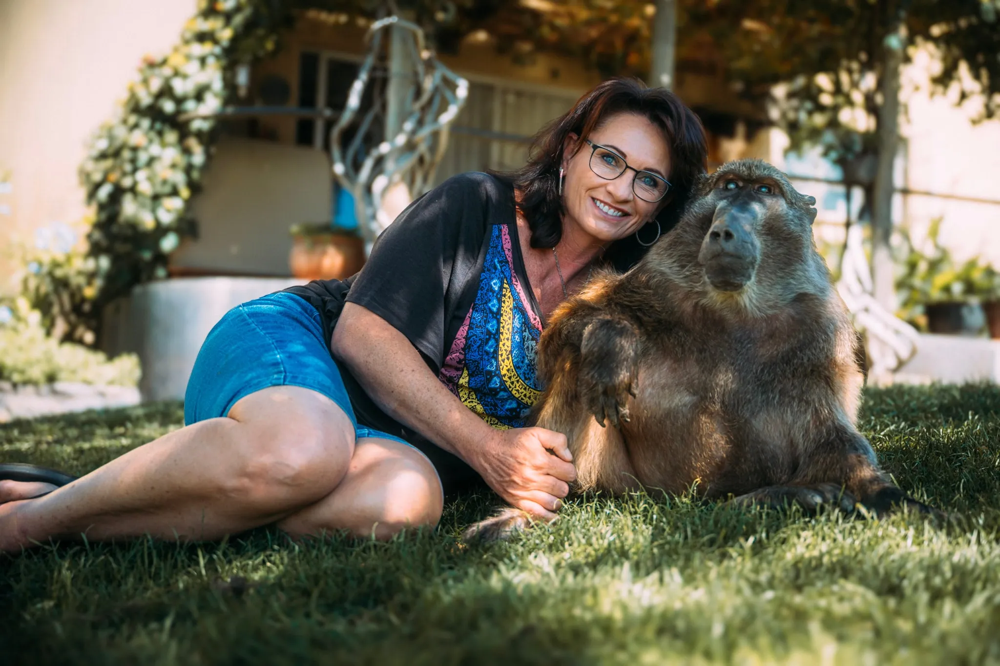 A family member sitting on the grass with Cindy the baboon